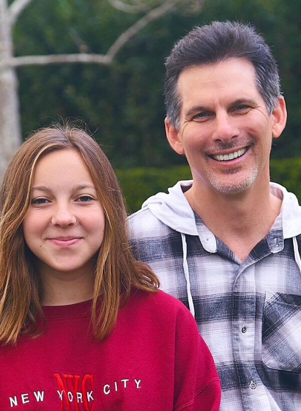 Portrait shot of Kevin DeMeritt with his daughter Aspen, both smiling. 